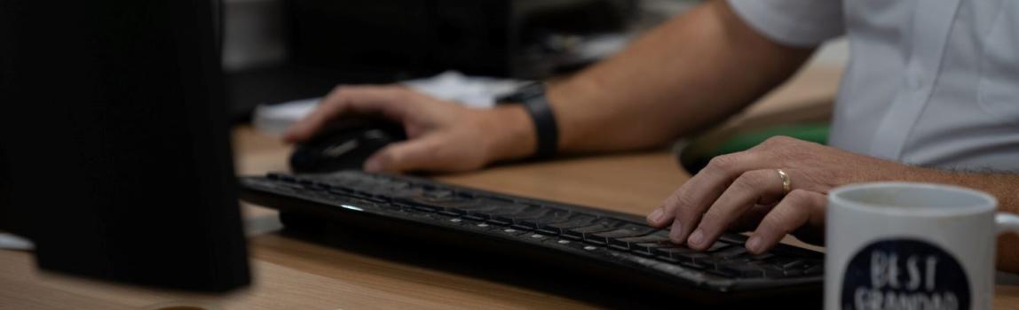 Man typing at a computer with notes