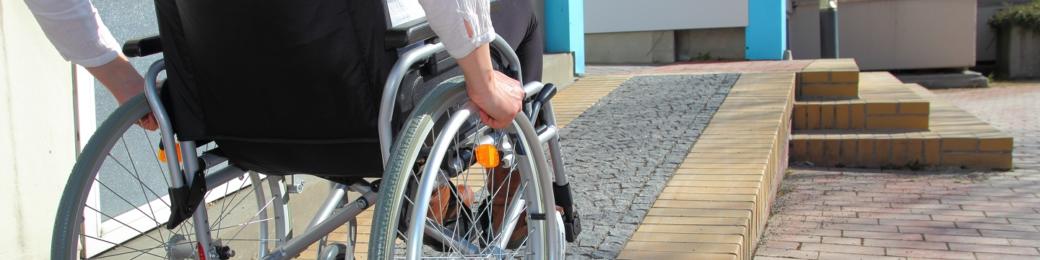 A person in a wheelchair uses a building access ramp.